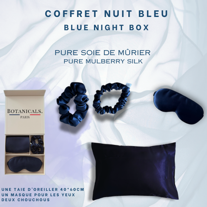 De gauche à droite: 
Un coffret ouvert Botanicals comprenant une taie oreiller, deux chouchous et un masque pour les yeux. Tout les produits sont en pure soie de murier et de couleur bleu nuit 