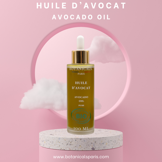 Une bouteille de 100ml d'huile d'avocat bio devant un fond rose, parsemé de léger nuage