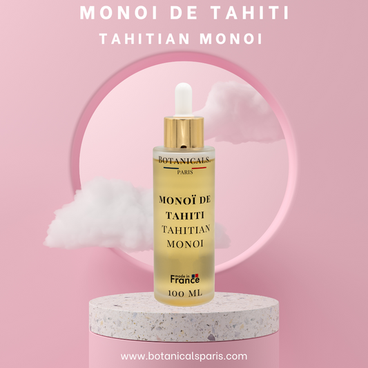 Une bouteille de 100ml de Monoi de Tahiti enrichi à l'huile de coco devant un fond rose, parsemé de léger nuage